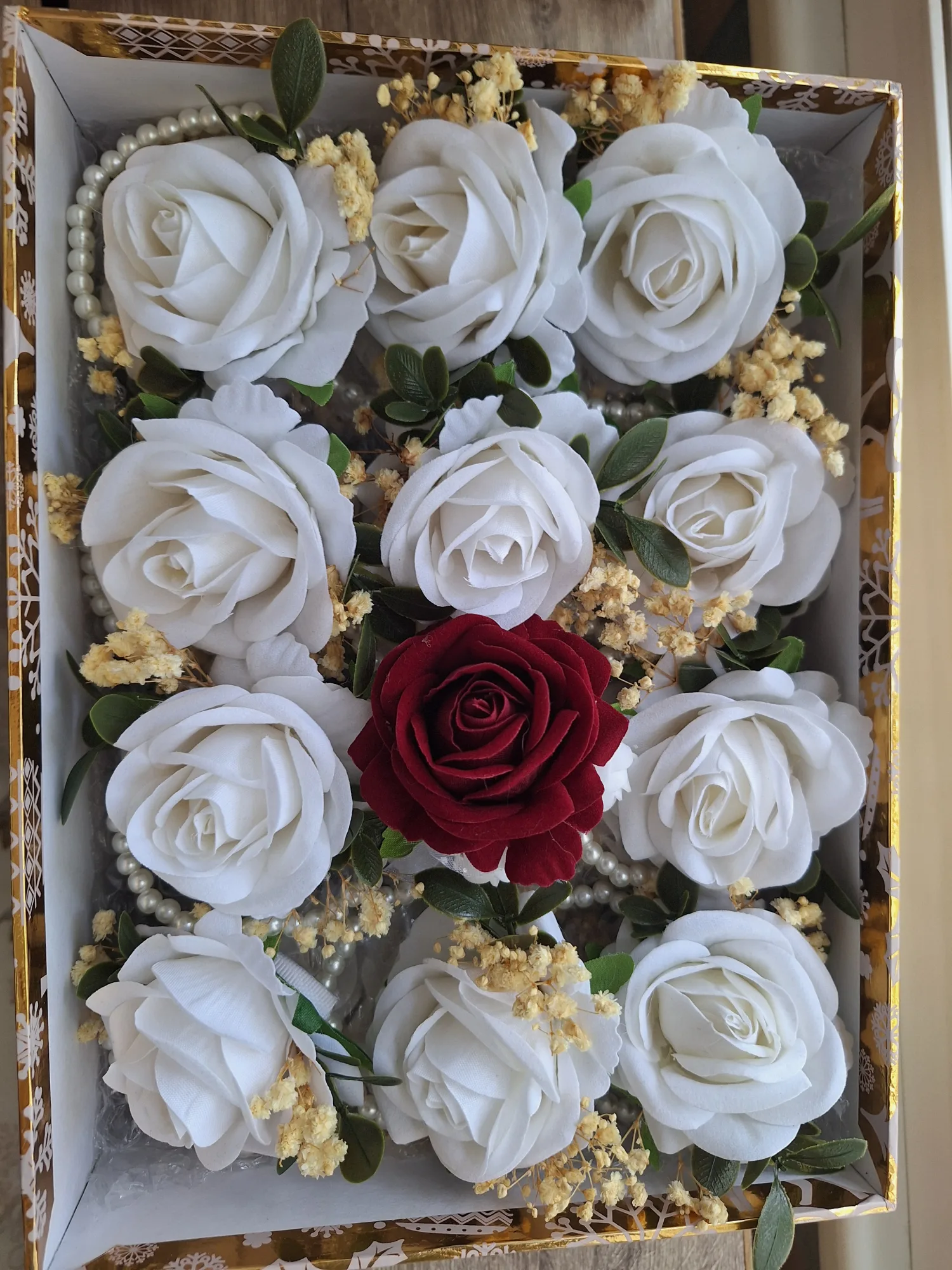 Wrist corsages with white rose, dried gypsophila and green leaves mounted on a pearl-bead bracelet and groom's boutonniere with burgundy rose.