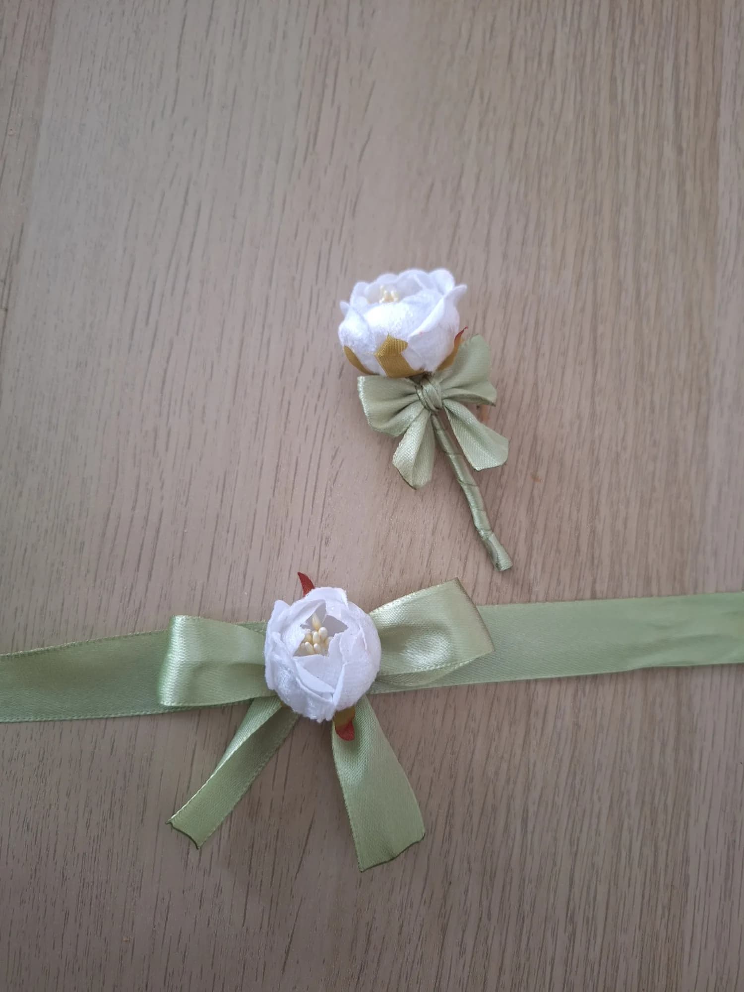 A set of white peony boutonniere and a corsage with an olive satin bow.