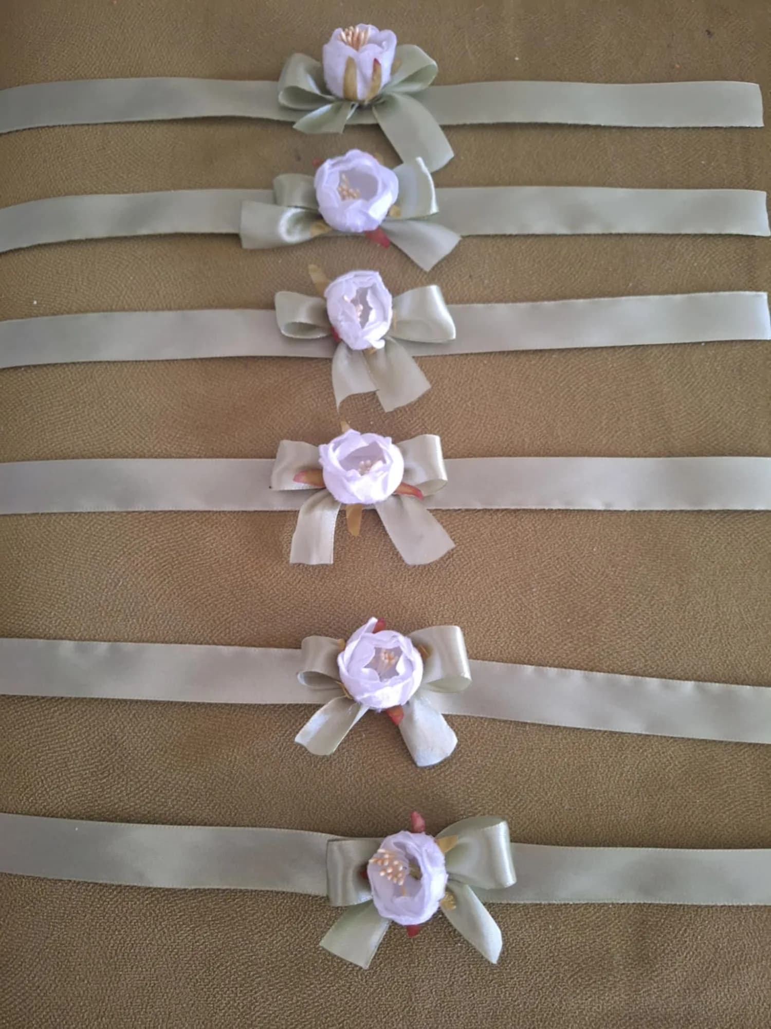 A set of white peony corsages with an olive satin bow.