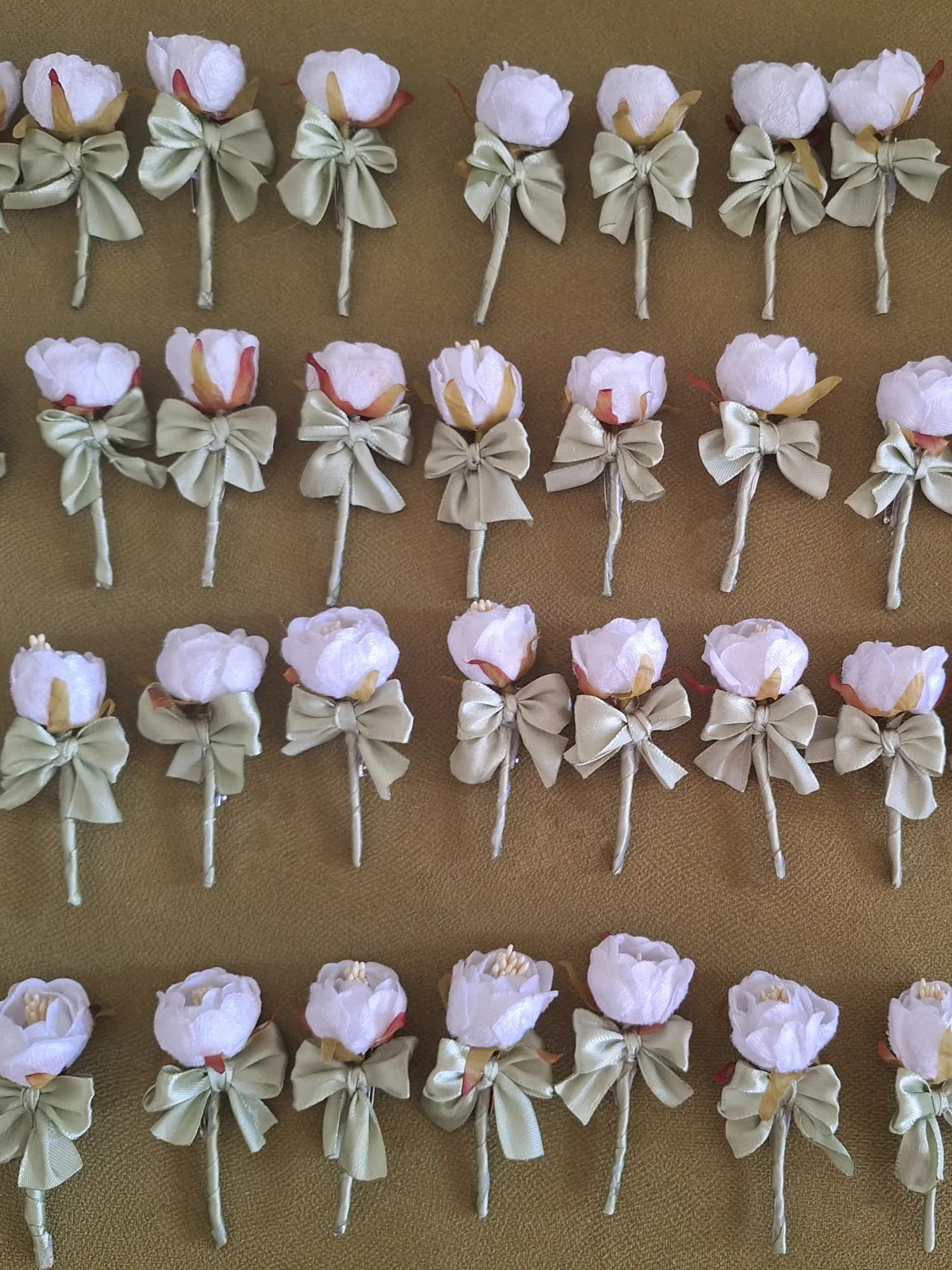 A set of white peony boutonnieres with olive satin bow.